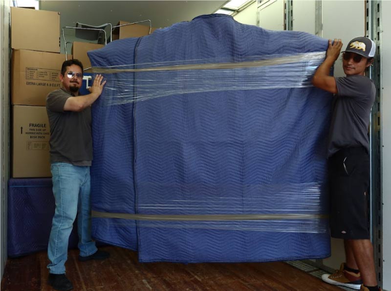 Team of professional movers carefully wrapping furniture for safe-keeping with All Cal Moving and their dependable storage near me in Visalia.